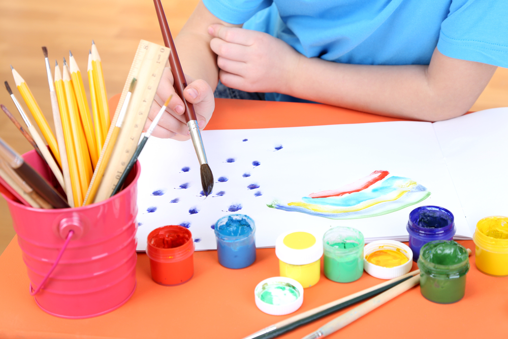 Niño pintando con témpera y pinceles