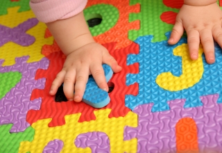 Manitas de bebé encima de puzzle de letras en el sueloletras