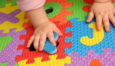 Manitas de bebé encima de puzzle de letras en el sueloletras